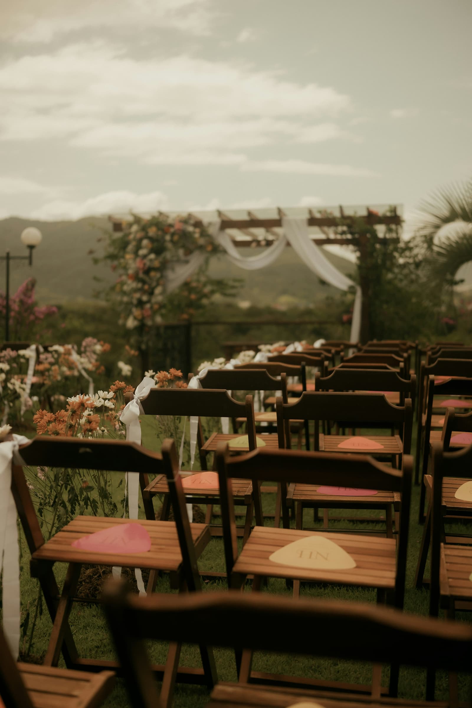 Rows of wooden chairs with program fans at an outdoor hillside wedding ceremony