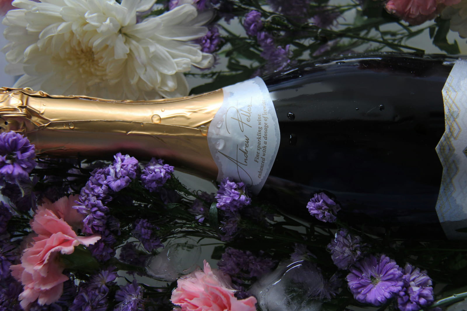 Styled wedding detail shot of a sparkling wine bottle resting among fresh flowers and ice
