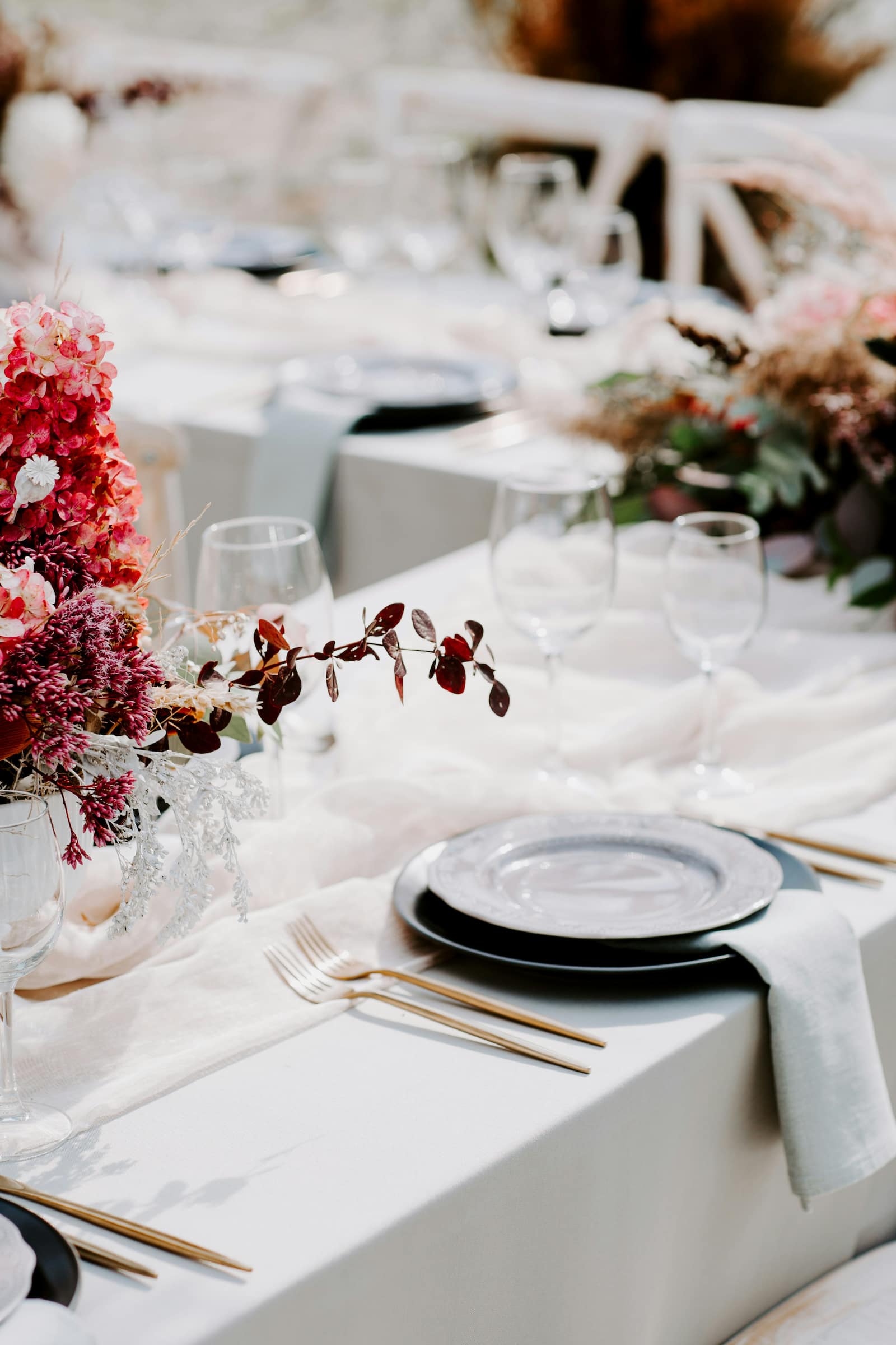 Elegant wedding reception table with gold flatware, black chargers, and pink floral centerpieces